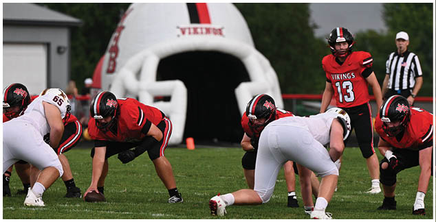 A group of football players in red and white uniforms are on a field. Description generated by AI