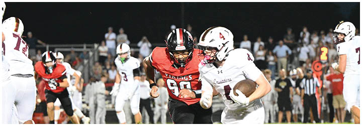 A football player in a red jersey is running with the ball. Description generated by AI
