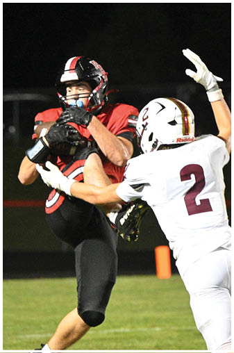 A football player in a black jersey catching a football. Description generated by AI