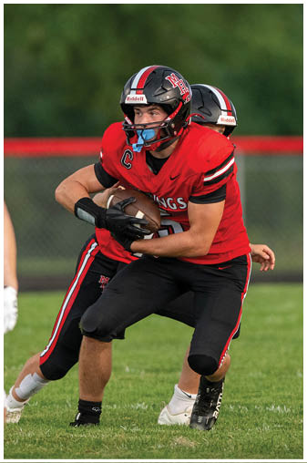 A football player in a red jersey is running with a football. Description generated by AI