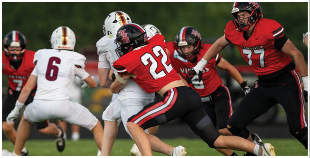 A football player in a red jersey is tackled by another player. Description generated by AI