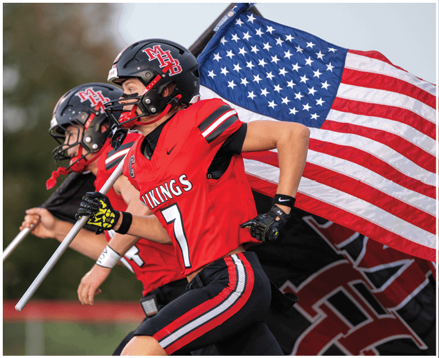 Two football players wearing red jerseys and black helmets. Description generated by AI