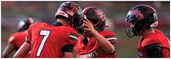 Three football players wearing red jerseys. Description generated by AI