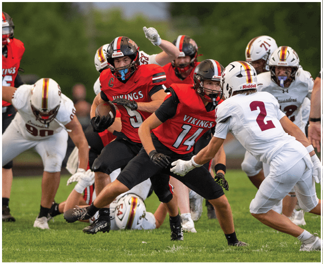 A football game is being played with a player in a red jersey running with the ball. Description generated by AI