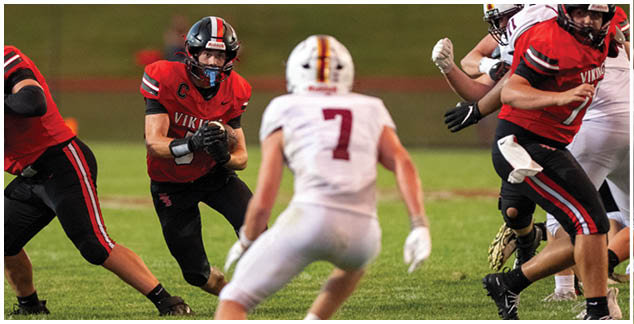 A football player in a red jersey is running with the ball. Description generated by AI