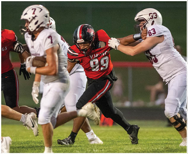 A football player in a red jersey is tackling another player. Description generated by AI