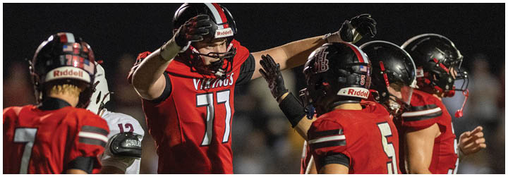 A football player wearing a red jersey with the number 77 on it. Description generated by AI