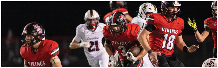 A group of football players in red and white uniforms running on a field. Description generated by AI