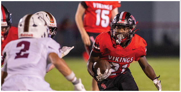 A football player in a red and black jersey with the number 24 on it. Description generated by AI
