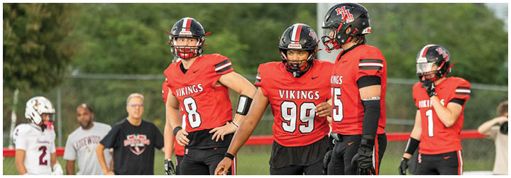 A group of football players wearing red and black uniforms. Description generated by AI