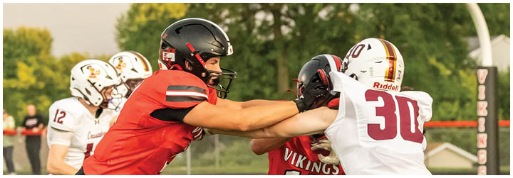 Two football players in red and white uniforms are fighting for a ball. Description generated by AI