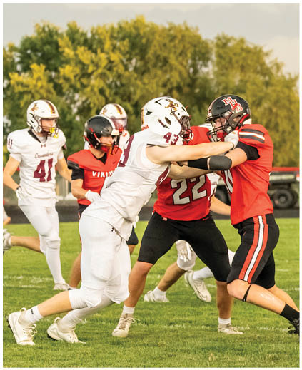 A football player in a red jersey is tackled by another player. Description generated by AI