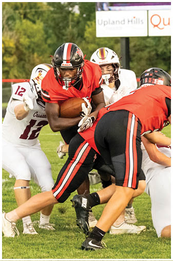 A football player in a red jersey is running with the ball. Description generated by AI