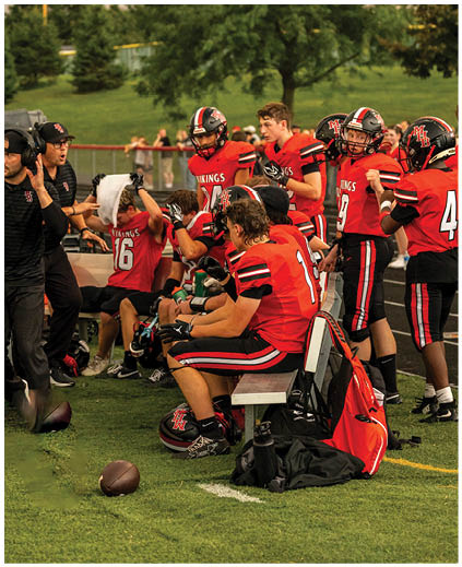 A group of football players sitting on the ground. Description generated by AI