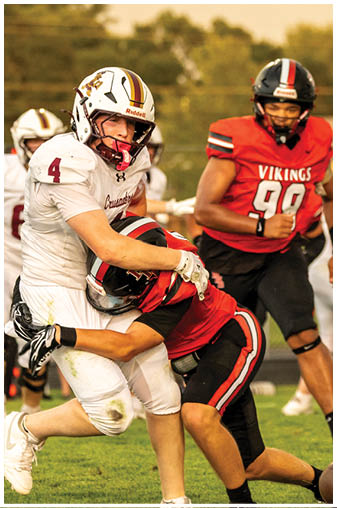 A football player in a red jersey is tackling another player. Description generated by AI