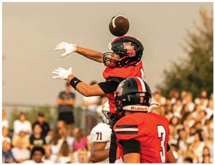 A football player in a red jersey catches a ball. Description generated by AI