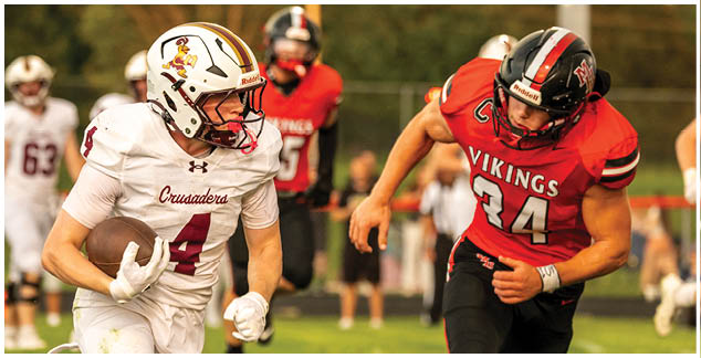 A football player in a white uniform running with a football. Description generated by AI
