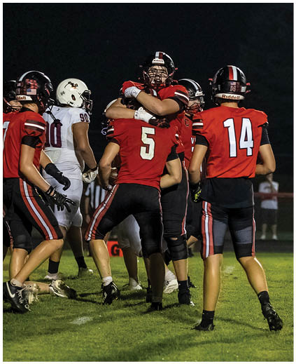 A group of football players hugging each other on the field. Description generated by AI