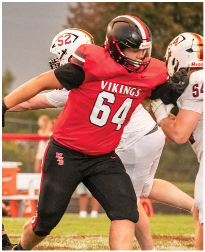 A football player wearing a red jersey with the number 64. Description generated by AI