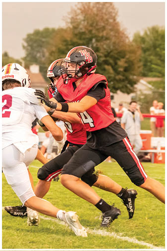 A football player in a red jersey is tackled by another player. Description generated by AI