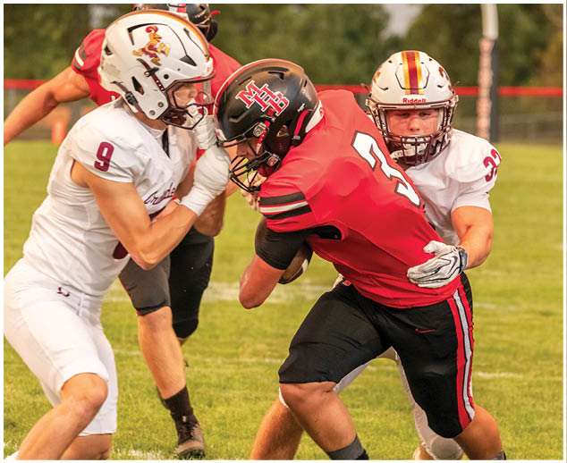 A football player wearing a red jersey is tackled by another player. Description generated by AI