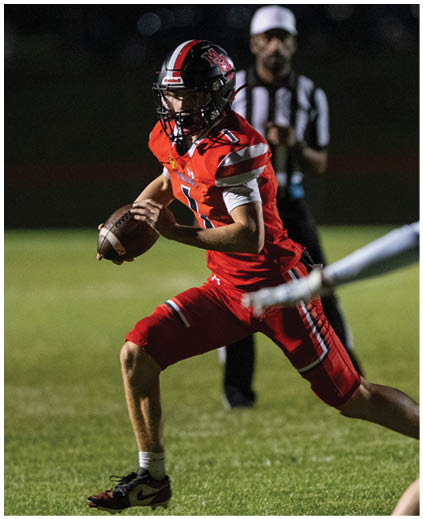 A football player in a red jersey with the number 12 on it. Description generated by AI