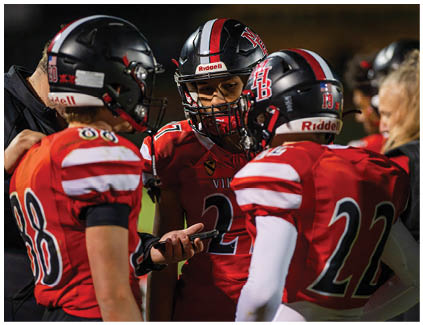 Three football players wearing red and black uniforms. Description generated by AI
