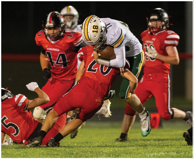 A football player in a red jersey is tackled by another player. Description generated by AI
