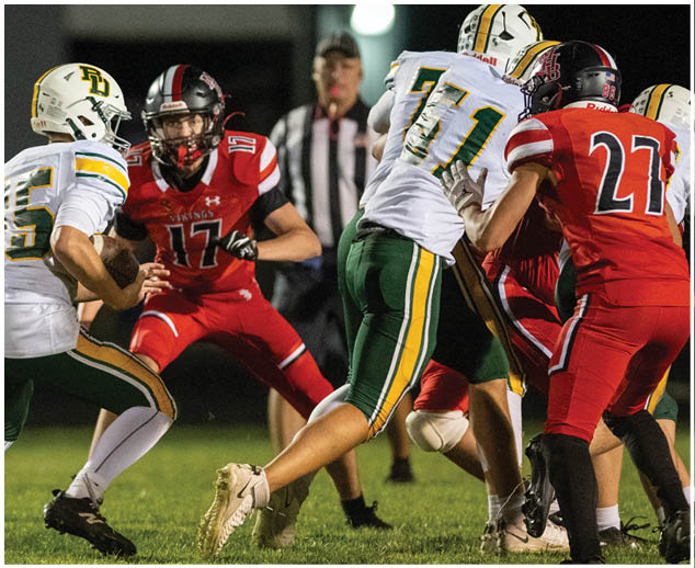 A football player in a red jersey is tackled by another player. Description generated by AI