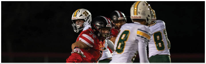 A football player in a red jersey is tackled by another player. Description generated by AI