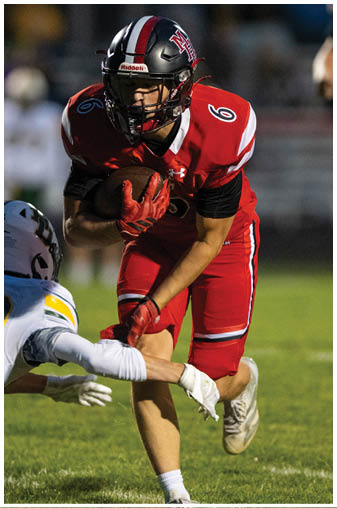 A football player in a red jersey is running with the ball. Description generated by AI
