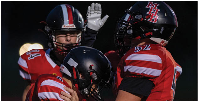 Two football players wearing red and black uniforms. Description generated by AI