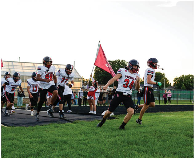 A group of people running on a field with a red flag. Description generated by AI