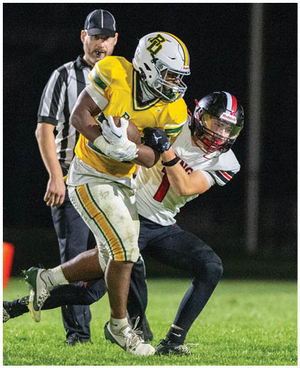 A football player in a yellow jersey is tackled by another player. Description generated by AI