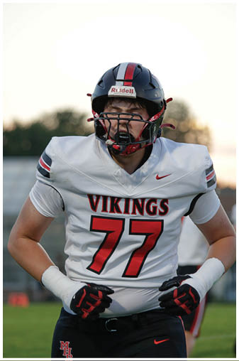 A football player wearing a white and red jersey with the number 77 on it. Description generated by AI