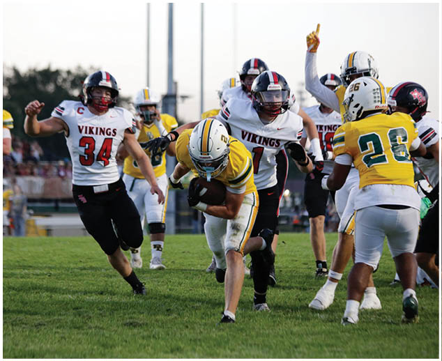 A football player in a yellow jersey is tackled by a player in a white jersey. Description generated by AI