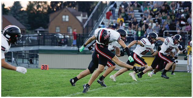A football game is taking place with players running on the field. Description generated by AI