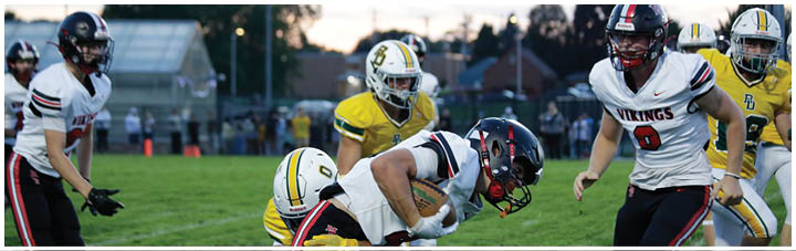 A football player in a yellow jersey tackles another player. Description generated by AI