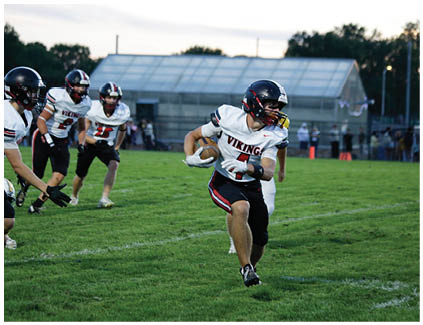 A football player running with a football. Description generated by AI
