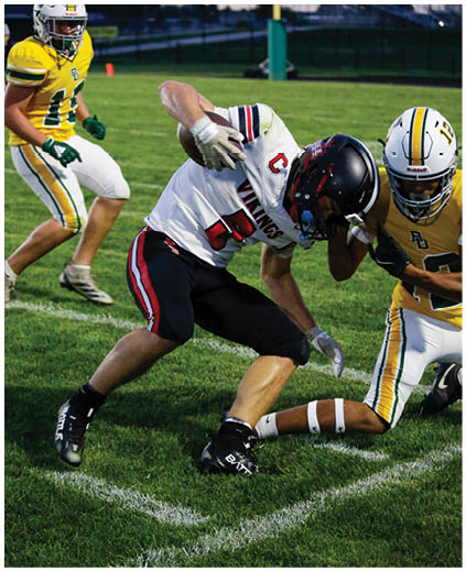 A football player in a white jersey is tackled by another player. Description generated by AI
