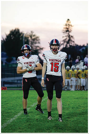 Two football players wearing black and white uniforms. Description generated by AI