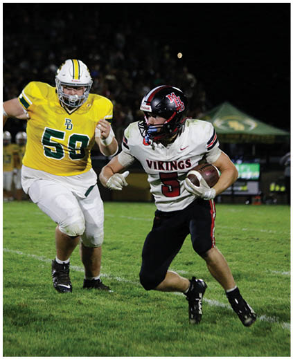 A football player in a yellow jersey is running with a football. Description generated by AI