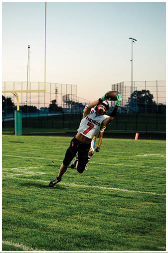 A man wearing a white jersey with the number 7 on it is jumping in the air to catch a football. Description generated by AI