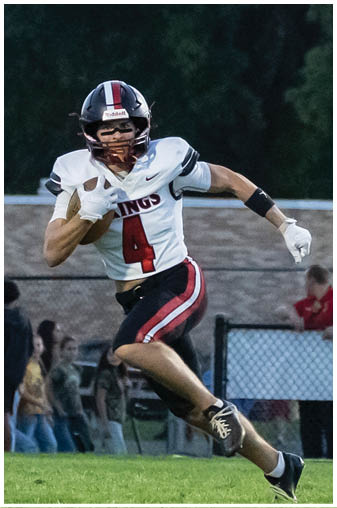 A man running on a field with a football jersey on. Description generated by AI