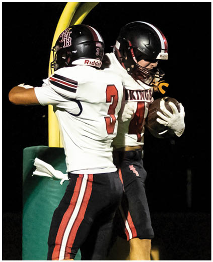 Two football players jumping for a ball. Description generated by AI