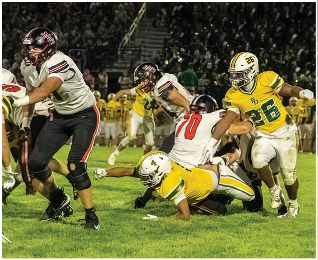 A football player in a yellow jersey is tackled to the ground. Description generated by AI