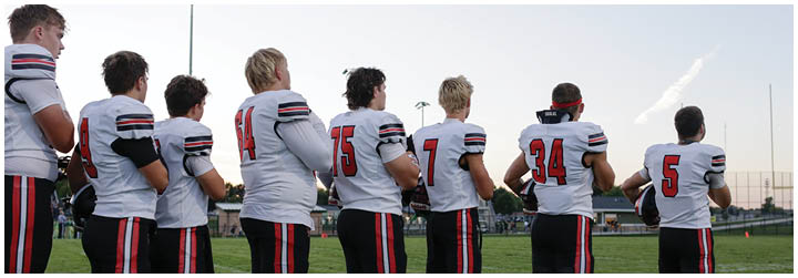 A group of football players standing on a field. Description generated by AI