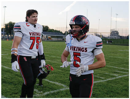 Two football players wearing black and white uniforms. Description generated by AI