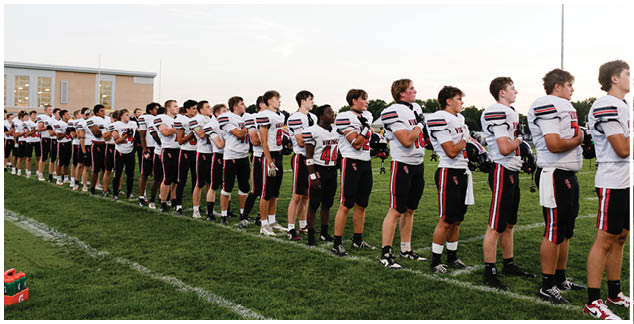 A group of football players standing on a field. Description generated by AI