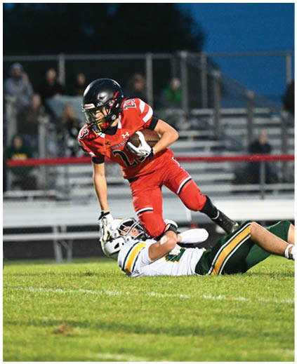 A football player in a red jersey is running with the ball. Description generated by AI